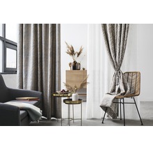 Living cu fotoliu, măsuțe laterale și ferestre decorate cu perdele