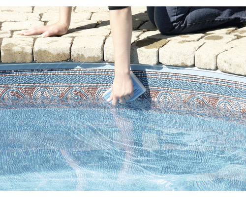 O persoană curăță o piscină cu un burete de curățare.