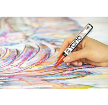 O mână pictând pe pânză cu un marker acrilic roșu Yono.