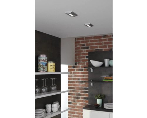 Scenă de bucătărie cu spoturi de tavan, perete de cărămidă și rafturi deschise cu veselă