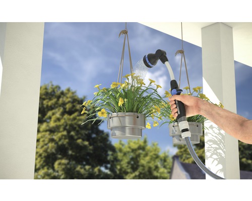 O persoană udă jardiniere suspendate cu un pistol de stropit pentru grădină.