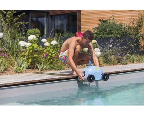 Un bărbat introduce un robot de curățare a piscinei în bazin.