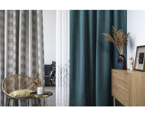 Interior decorativ cu diverse perdele, un scaun de ratan și un dulap din lemn