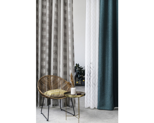 Cameră de zi cu fotoliu din ratan, măsuță laterală și diverse perdele cu modele