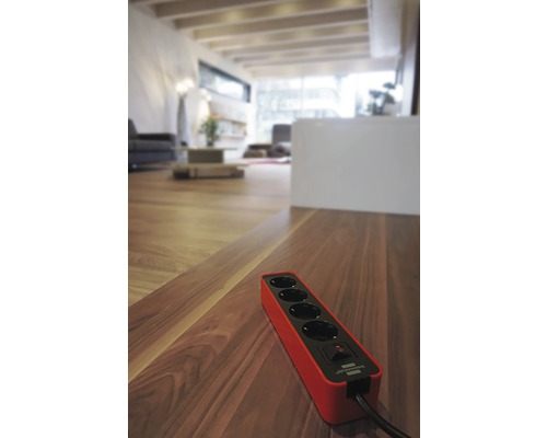 Prelungitor cu patru prize pe podea de lemn în camera de zi