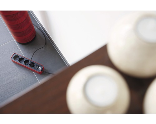 Prelungitor cu patru prize și porturi USB pe o podea cu gresie gri