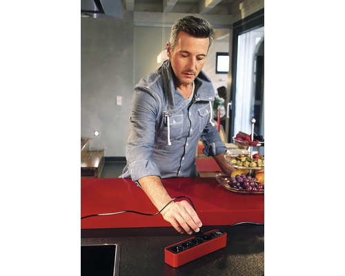 Un bărbat introduce o priză într-o priză multiplă într-o bucătărie.