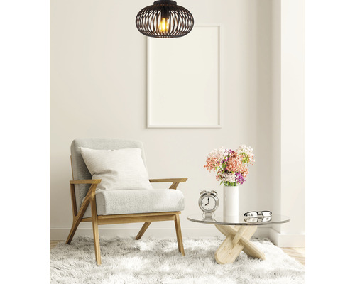 Cameră de zi cu fotoliu, măsuță de cafea și o lampă suspendată neagră