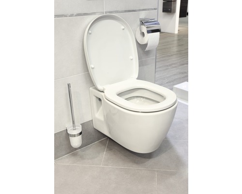 WC suspendat cu capac deschis, perie de toaletă și suport de hârtie într-o baie.