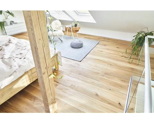 Mansardă luminoasă cu podea de lemn, pat, covor și zonă de relaxare