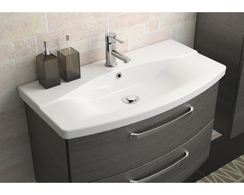 Chiuvetă cu dulap inferior, robinet, dozator de săpun și pahar pentru periuțe de dinți pe o chiuvetă de baie