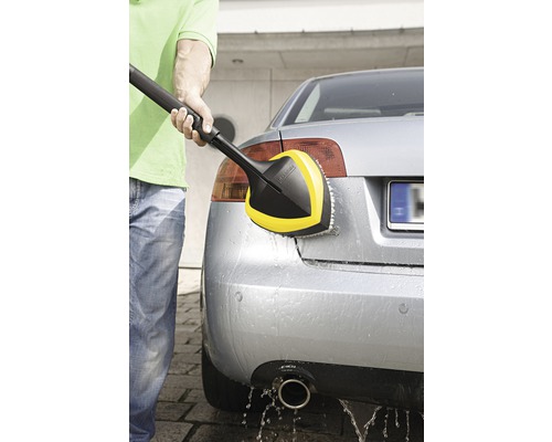 O persoană curăță o mașină cu o perie rotativă de spălare Kärcher.