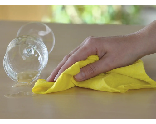 Putere de curățare: mână șterge băutura vărsată cu o cârpă de curățare pe masă.