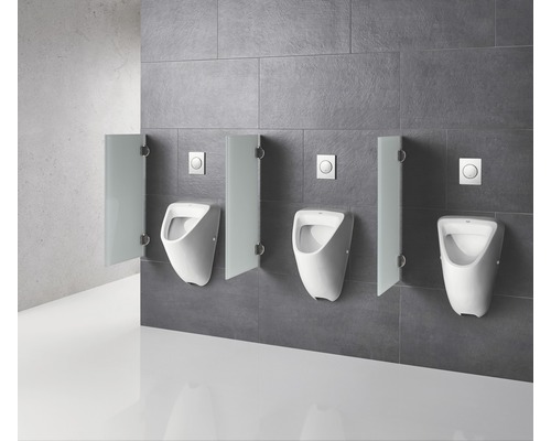 Trei pisoare albe cu separatoare și butoane de spălare pe un perete gri