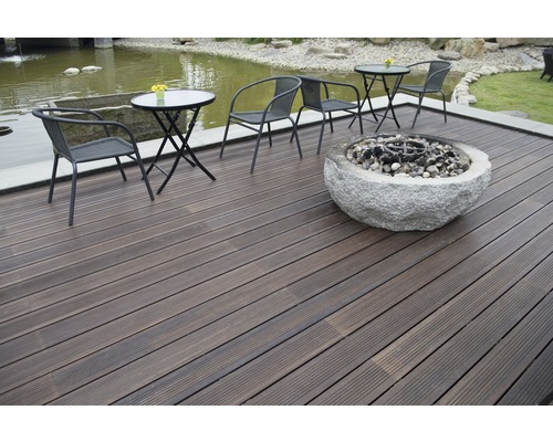 Terasa cu scânduri de lemn închise la culoare, zonă de relaxare și vatră de piatră.