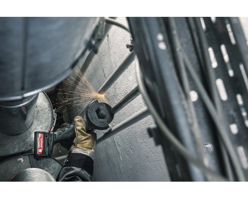 O persoană folosește un polizor unghiular cu acumulator pentru a tăia o țeavă metalică, producând scântei.