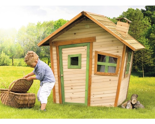 Copil cu coș de picnic în fața unei căsuțe de joacă din lemn în grădină.