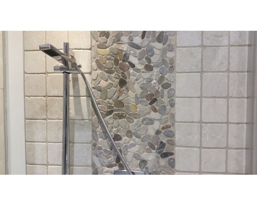 Prim-plan al unui cap de duș pe un fundal de pietricele și plăci