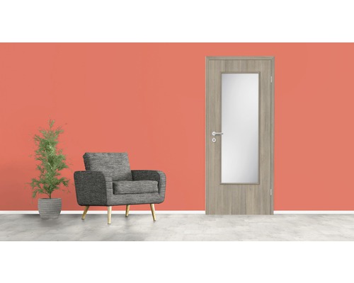 Ușă de interior din lemn cu inserție de sticlă, fotoliu și plantă în ghiveci în fața unui perete