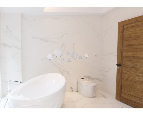 Baie modernă cu cadă freestanding, toaletă și oglinzi rotunde ca decor