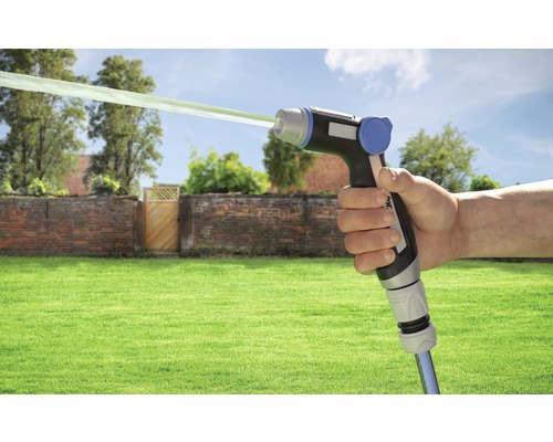 Mână ținând pistol de stropit cu jet de apă în fața peisajului de grădină