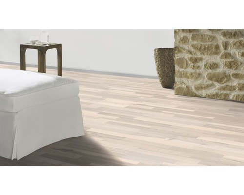 Pardoseală deschisă la culoare din lemn într-un living cu decorațiuni din piatră și mobilă albă.