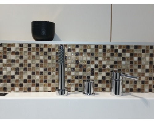 Baterie de baie cu duș de mână în fața plăcilor de mozaic