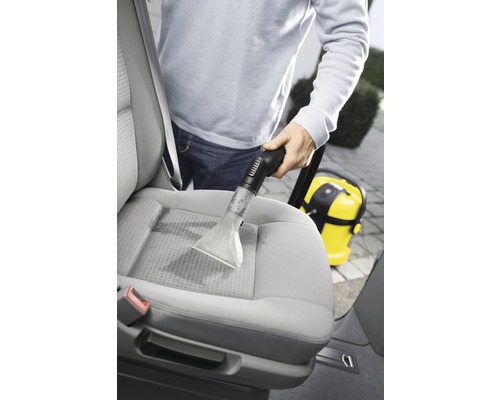 Persoană curățând un scaun auto cu un aspirator de spălat