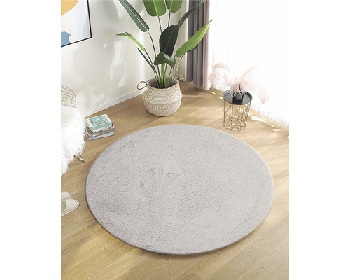 Amenajare cu covor rotund din fibre sintetice pe podea de lemn într-o cameră luminoasă.