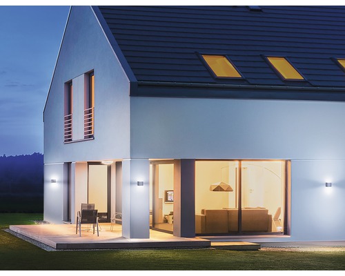 Casă modernă cu iluminat exterior și terasă în grădină.