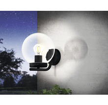 Lampa de perete cu abajur rotund de sticlă și bec pe un perete