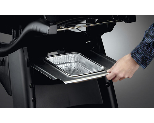 O persoană introduce o tavă de scurgere din aluminiu într-un grătar.