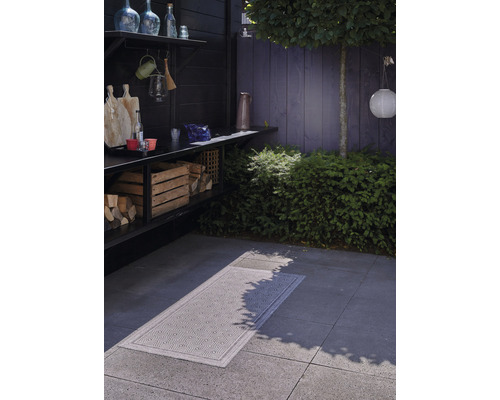 Spațiu exterior cu depozit de lemne, blat de lucru și covor cu model pe sol.