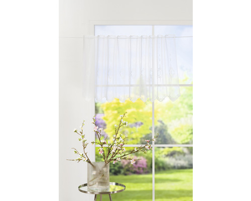 Fereastră decorativă cu draperie vitrată albă și decorațiuni de primăvară