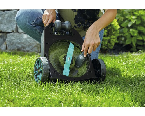 O persoană curăță o mașină de tuns iarba pe un gazon.