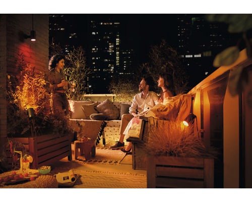 Terasa atmosferică pe acoperiș cu iluminat exterior și oameni relaxați pe timp de noapte.