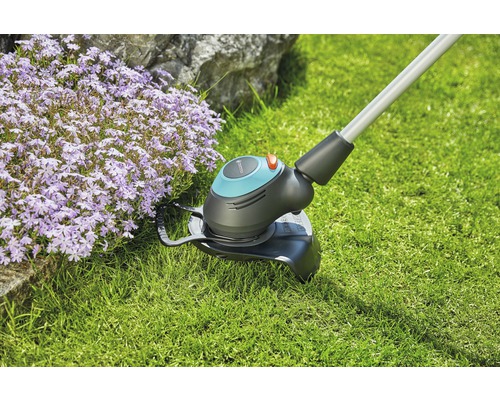 Trimmer de gazon în funcțiune lângă stratul de flori