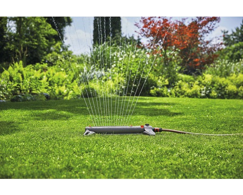 Aspersor de gazon în funcțiune pe un gazon verde