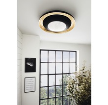 Fotografie de interior a unei camere cu o lampă de tavan rotundă din metal și plastic