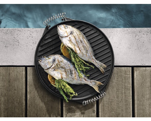 Doi pești Sparus aurata la grătar pe o plită, cu ierburi aromatice și felii de lămâie.