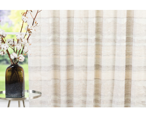 Perdea decorativă cu model în dungi lângă o masă cu o vază cu flori.