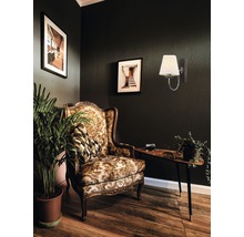 Cameră de zi decorativă cu fotoliu, masă, lampă de perete și plantă de interior