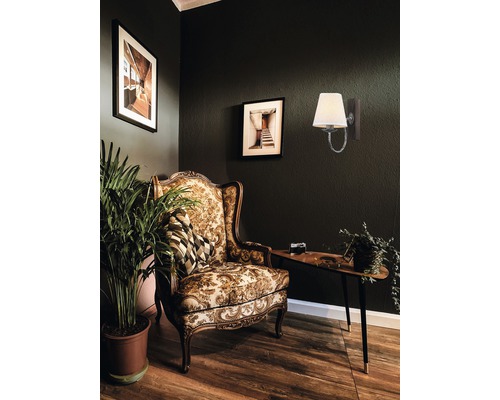 Cameră de zi decorativă cu fotoliu, masă, lampă de perete și plantă de interior