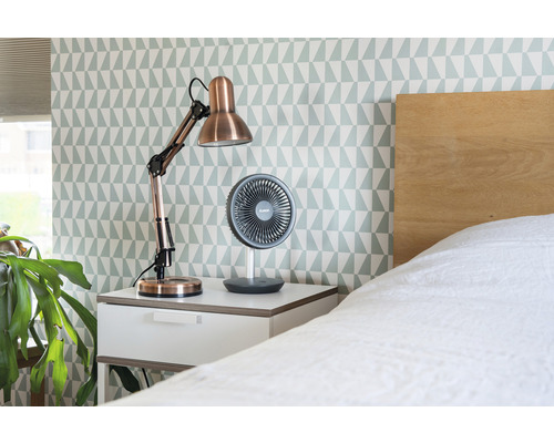 Noptieră cu lampă de birou și ventilator în dormitor.
