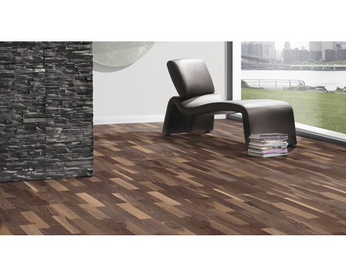 Cameră de zi cu podea laminată cu aspect de lemn, fotoliu și perete de piatră