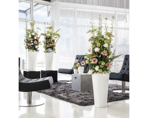 Interior luminos cu aranjamente florale în jardiniere înalte, fotolii și covor