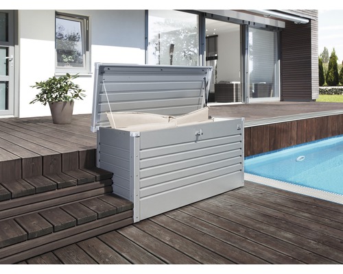 Cutie de depozitare metalică deschisă cu perne pe o terasă de lemn lângă o piscină