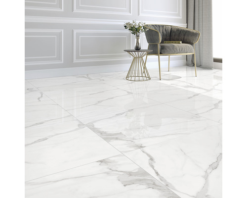 Cameră luminoasă cu gresie lucioasă cu aspect de marmură, fotoliu și măsuță laterală.