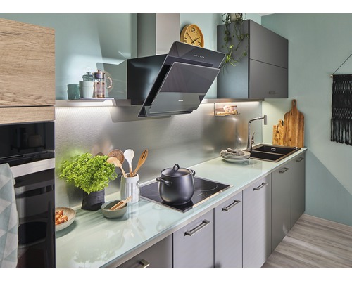 Bucătărie luminoasă cu hotă, chiuvetă și plită.