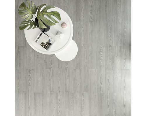 Suprafață de podea cu aspect de lemn deschis, cu o masă rotundă albă și o plantă
